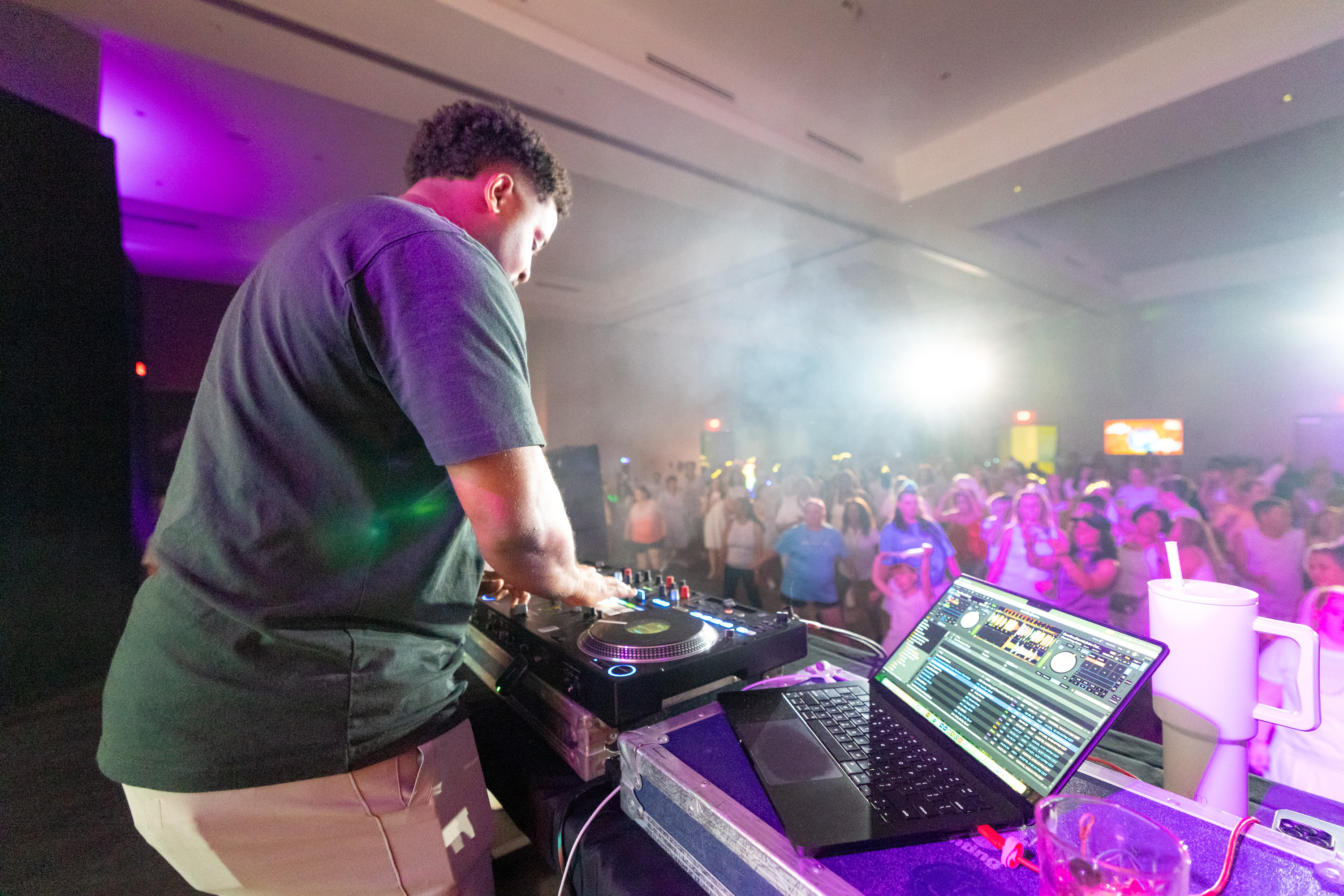 A DJ on stage spinning for a packed, dancing crowd