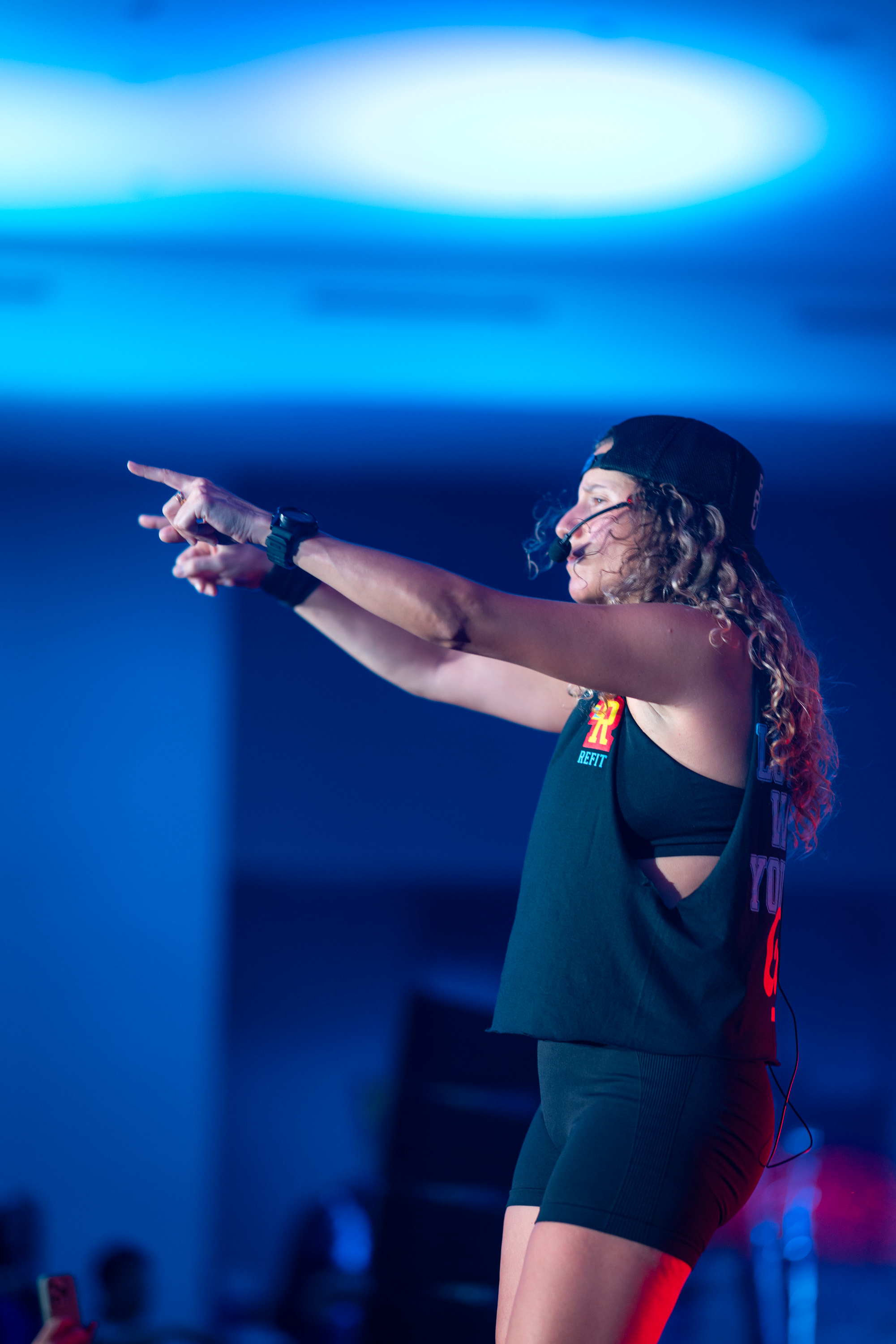 A REFIT Instructor on stage with a headset mic, pointing to the crowd